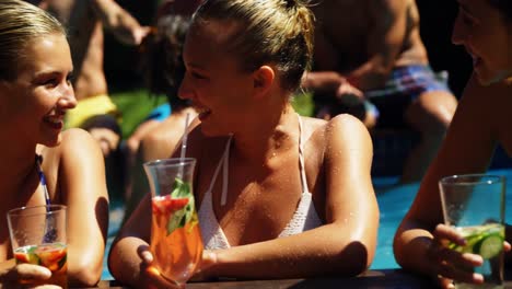 smiling womens drinking cocktails and having fun in swimming pool