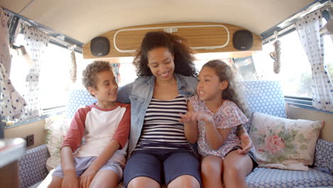 smiling mum and kids travelling in the back of a camper van
