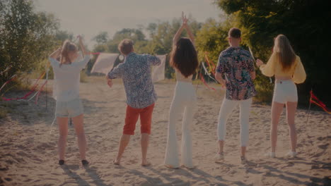 young male and female friends dancing at beach