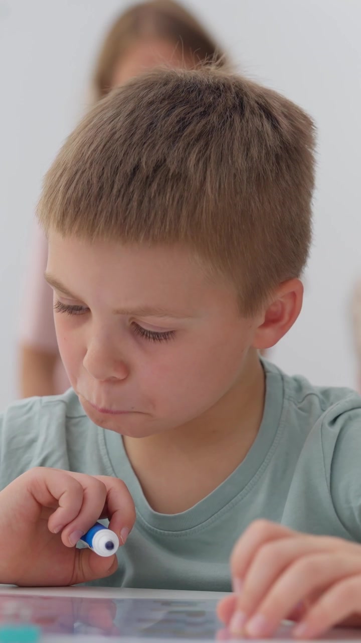 Giovane ragazzo concentrato mentre disegna con un pennarello
