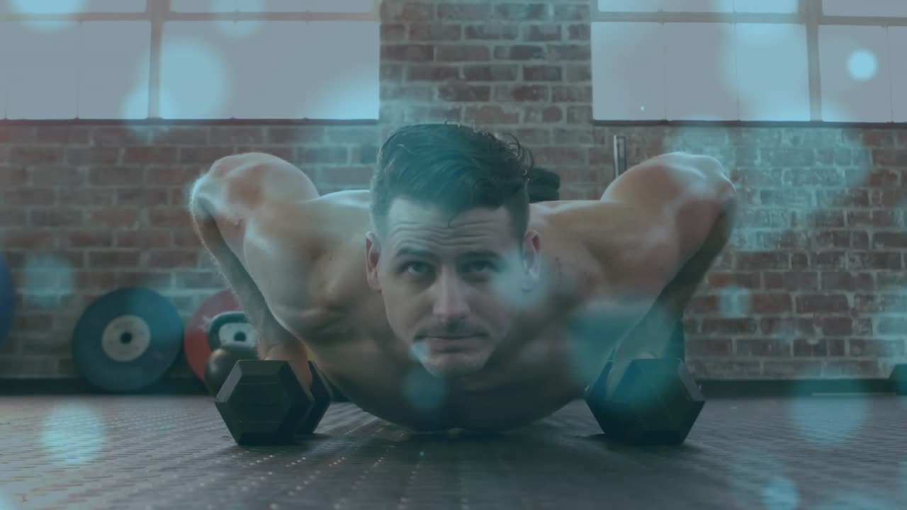 Man starting from floor holding hex dumbbells bracing and pushing up for fitness blue bokeh overlay