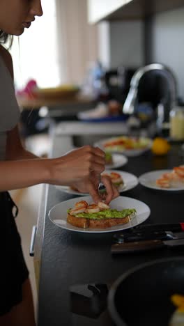 mujer preparando tostadas de aguacate con camarones