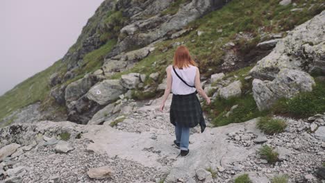 a young woman hiker climbs mountains with photo camera. transfagarasan, carpathian mountains in romania