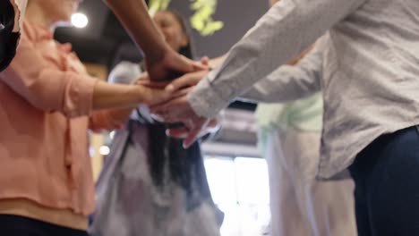 Happy-diverse-businesswomen-stacking-hands-together-at-office,-in-slow-motion