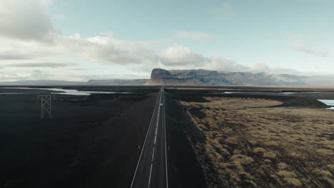 car drives long straightaway through black sand desert in iceland