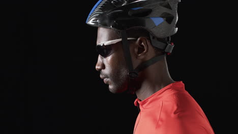 african american cyclist in cycling gear poses confidently on a black background, with copy space