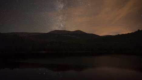 lapso nocturno del movimiento de las estrellas y la vía láctea sobre la montaña moncayo, con reflejo en el lago