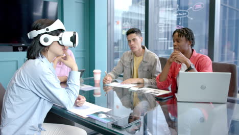 using vr headset, woman presenting to colleagues with laptops in modern office