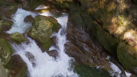 close up shot of small waterfall flows down the rocks in river during sunlight