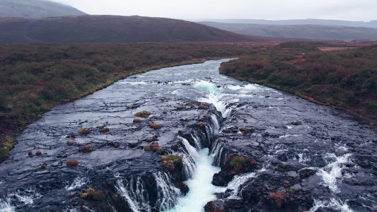 aerial: sobrevuelo bruarfoss cascada de agua fuera del círculo dorado en el sur de islandia que es muy pintoresco con la hermosa cascada azul de caídas en la piscina de inmersión debajo