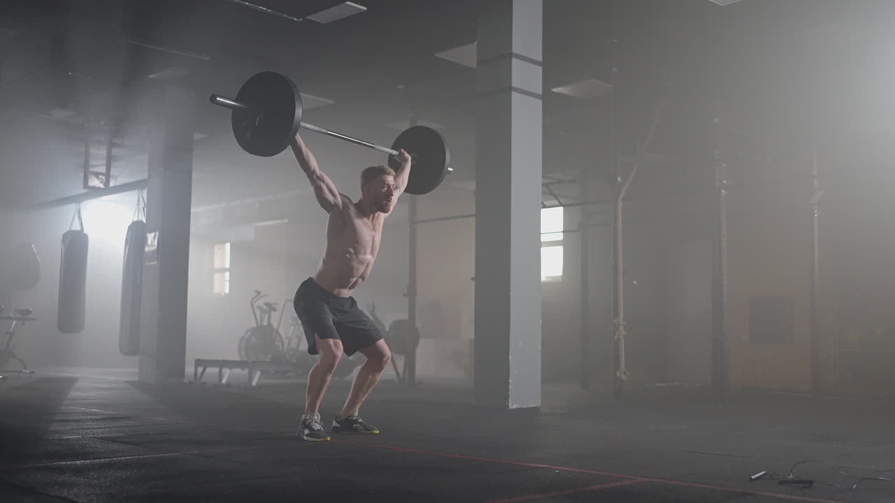 A young male weightlifter lifts a heavy barbell over his head performing a jerk. the jerk of a heavy barbell in slow motion
