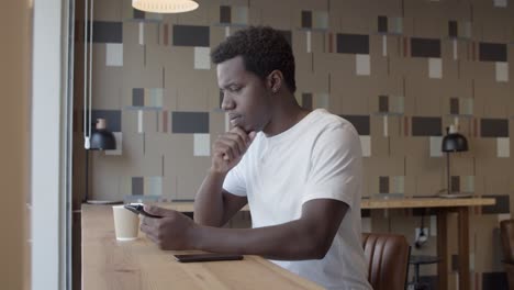 joven afroamericano enfocado usando tableta y hablando solo