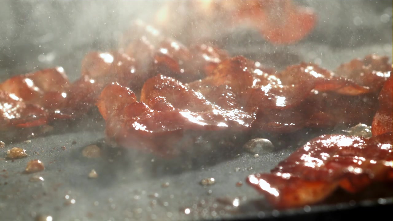 Primo piano di pancetta che frigge e sfrigola su una padella calda