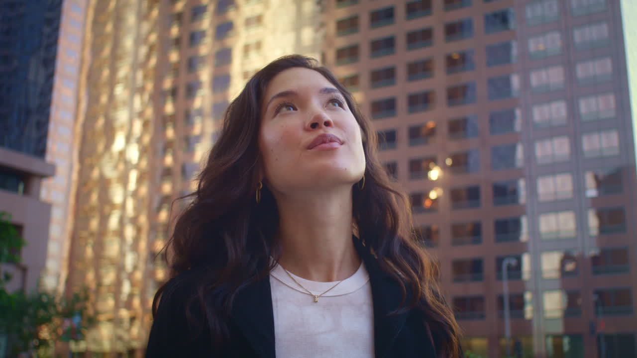 retrato de una mujer mirando hacia arriba en los edificios. mujer asiática explorando la ciudad de cerca.