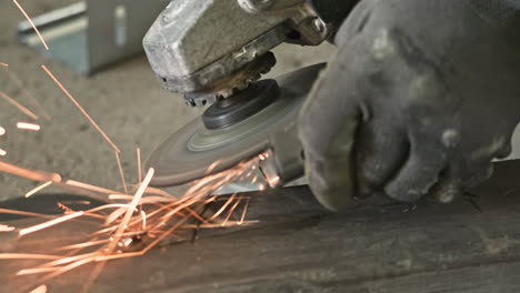 la mano del lavoratore con i guanti utilizzando una smerigliatrice angolare e genera scintille - primo piano