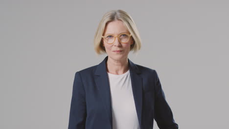 Studio-Portrait-Of-Serious-Mature-Businesswoman-Wearing-Glasses-Against-Plain-Background