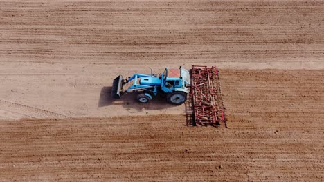 top down drone view of old blue tractor plowing spring soil, sunny latvian day