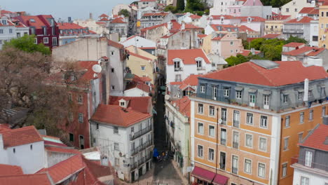 Cámara-De-Drones-Volando-Cerca-De-Las-Casas.-Vuelo-Bajo-Sobre-Tejados-Rojos.-Calles-Estrechas-Y-Sinuosas-En-La-Parte-Vieja-De-La-Ciudad.-Lisboa,-Capital-De-Portugal.