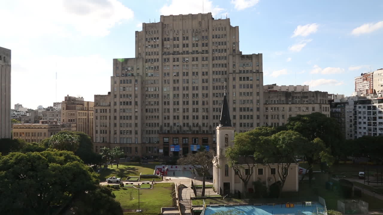 Escena urbana con un edificio imponente, iglesia y parque público