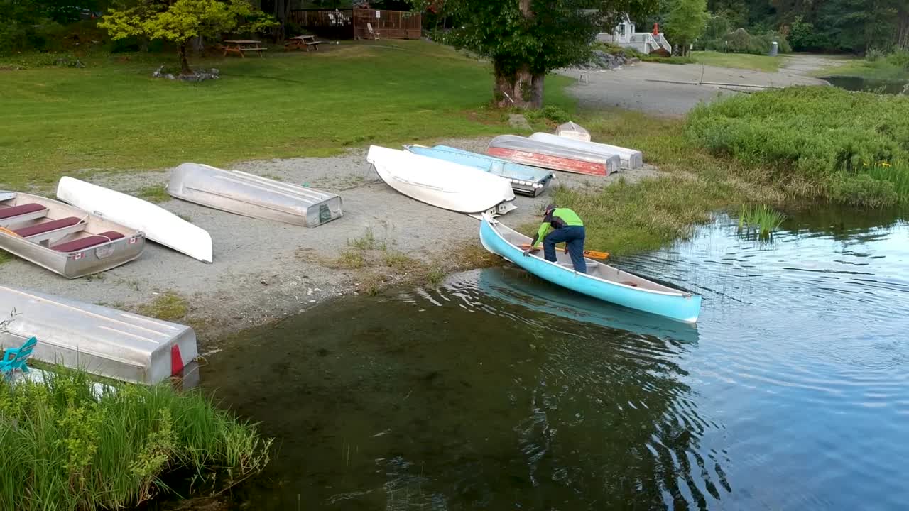 남자는 bc 캐나다의 호수에서 카누를 타고 해안으로 올라옵니다.