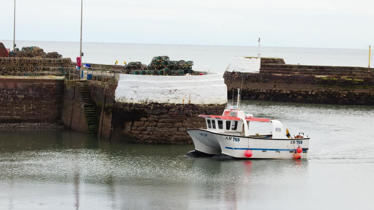 Small fishing boat navigates calm harbor waters, stone pier, overcast lighting, steady wide shot
