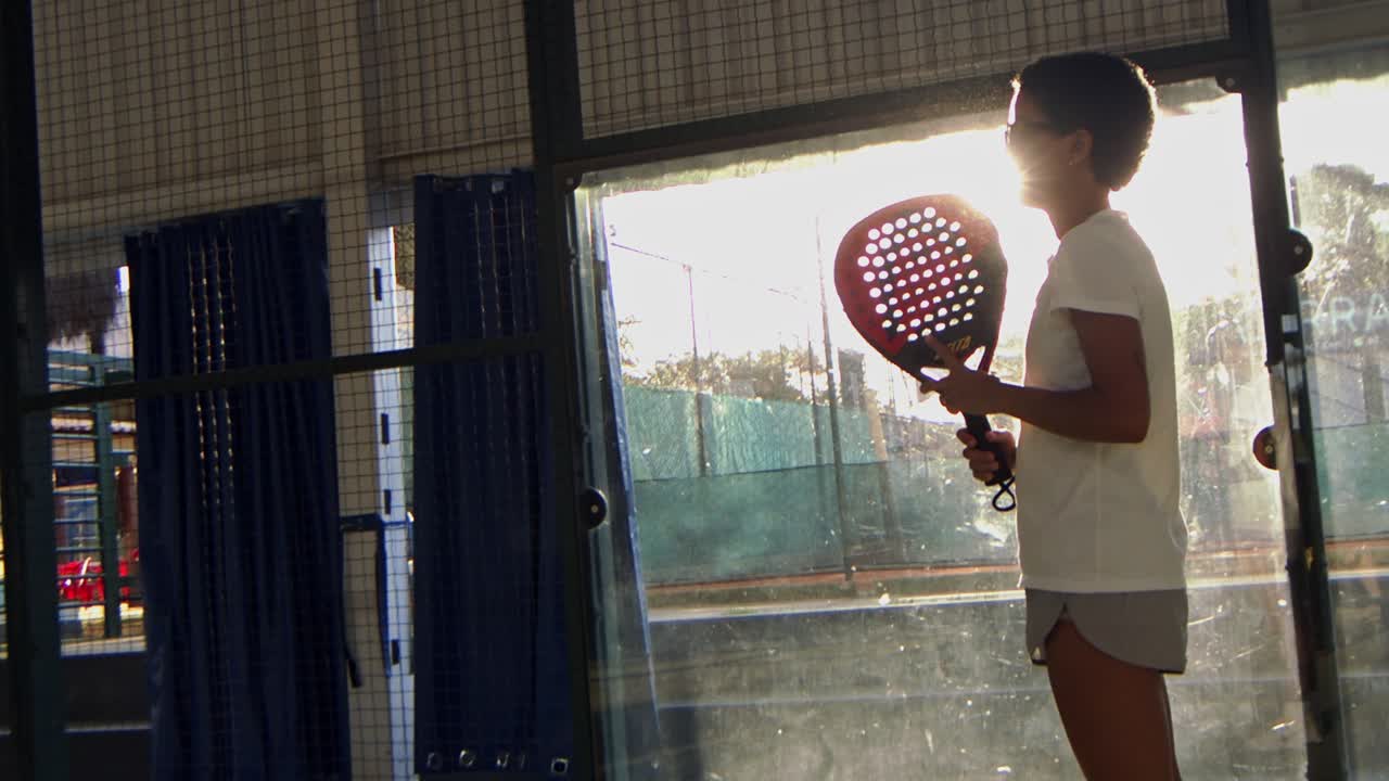 Black woman playing Padel waits for he opponent to serve the ball