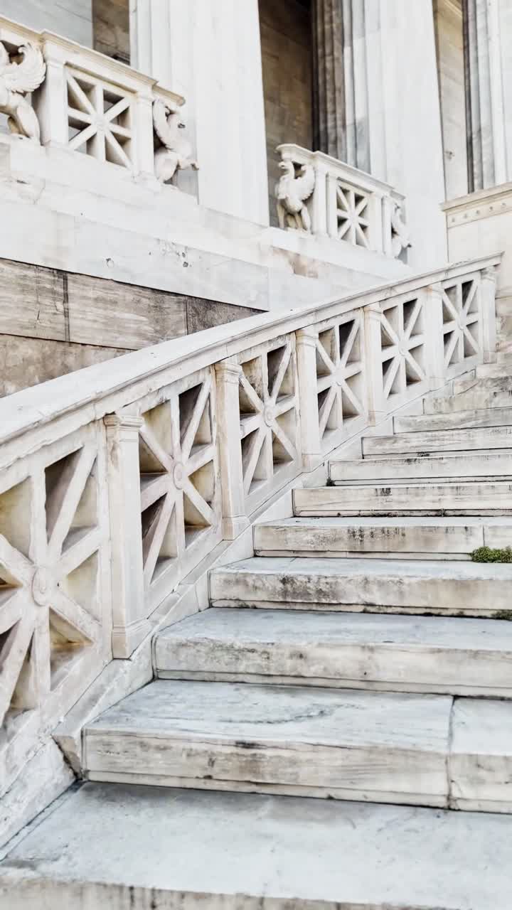 Tourist walking up the white marble stairs of the University of Athens