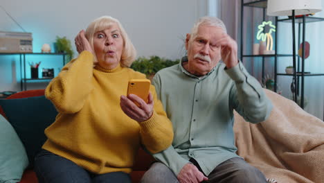 Senior man woman couple use smartphone surprised by bad news fortune loss fail lottery results