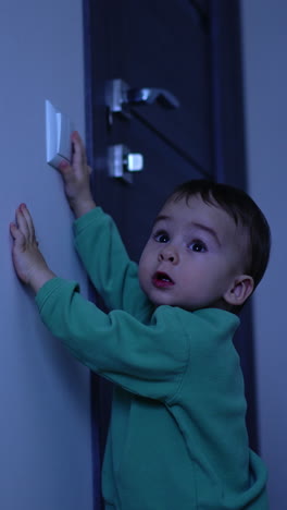 little child playing with the light. adorable kid riches his hand to the switch and turns the light on. baby boy looks up curiously at the lamp. vertical video