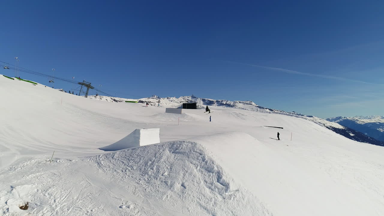 Dynamic freestyle skier throwing big airs and stylish tricks on rails at Laax Snowpark, Switzerland—capturing high-level performance, style, and action in a world-class winter setting.