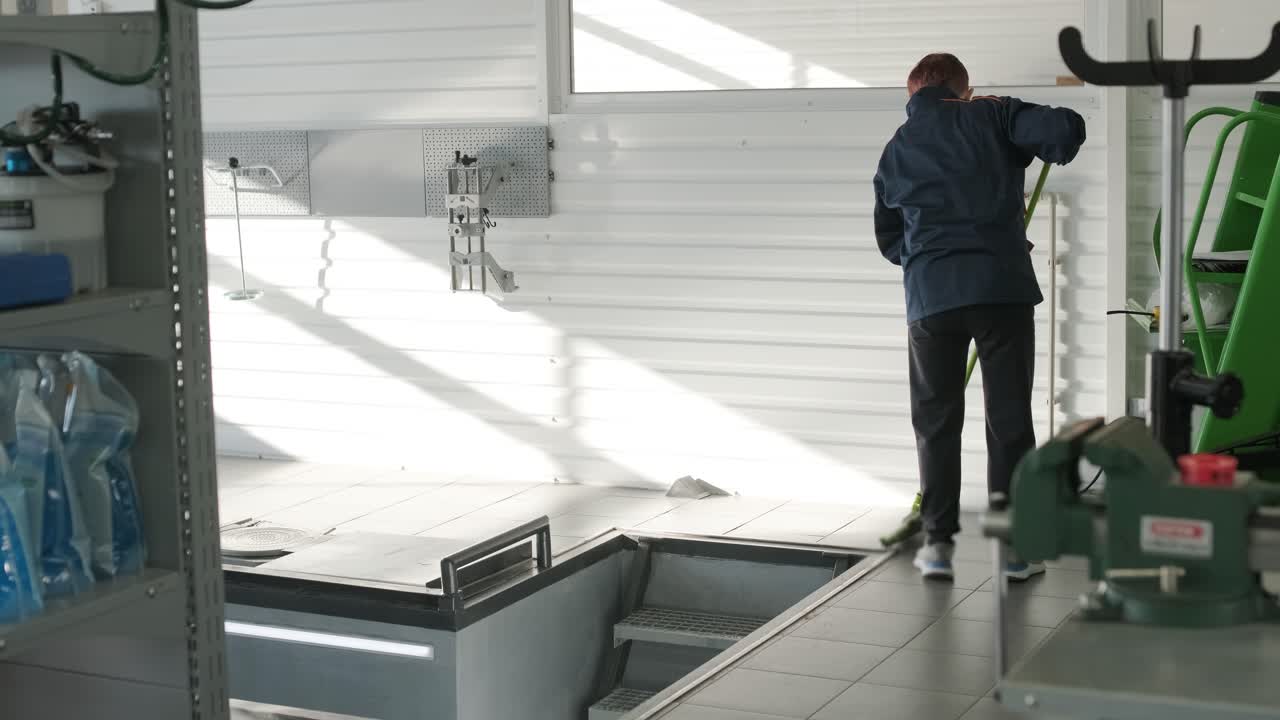 Operaio che pulisce un'autofficina.