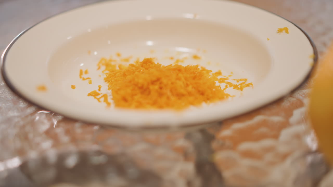 Orange zest on plate, pumpkin pie. Home baker prepping garnish in warm kitchen porcelain bowl resting on textured glass table bright orange shavings clustered in center soft natural light and subtle