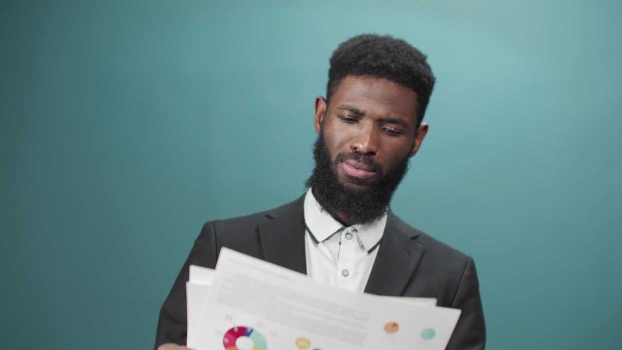An african businessman is looking through documents then throwing it away aggressively
