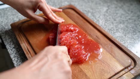 Close-Up-of-A-Person-Slicing-And-Chopping-Tomatoes-Using-a-Knife-On-Wooden-Board