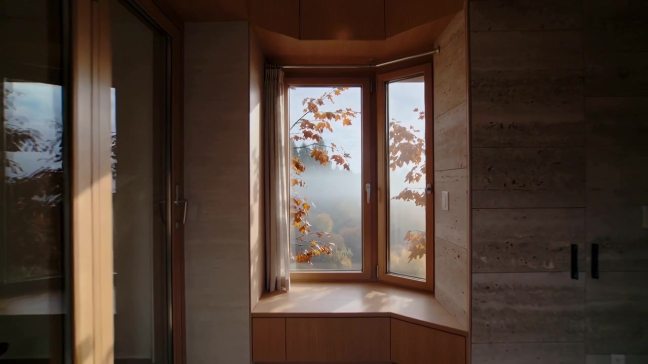 Pulling back camera revealing wood-framed bay window centered in cabin nook, showing bench and fog