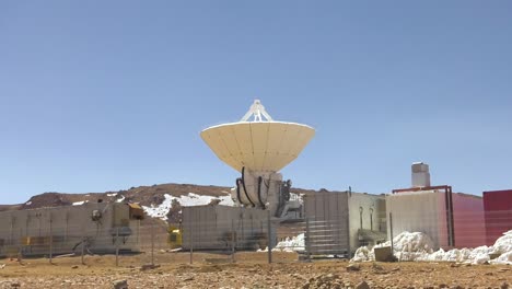 una toma del sitio de un telescopio del observatorio alma, contenedores parados al lado