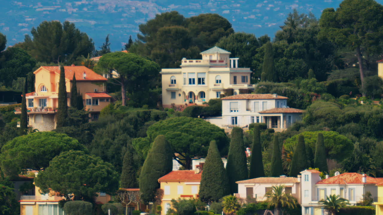 Distant view of multiple villas surrounded by green trees with the mountains on the background