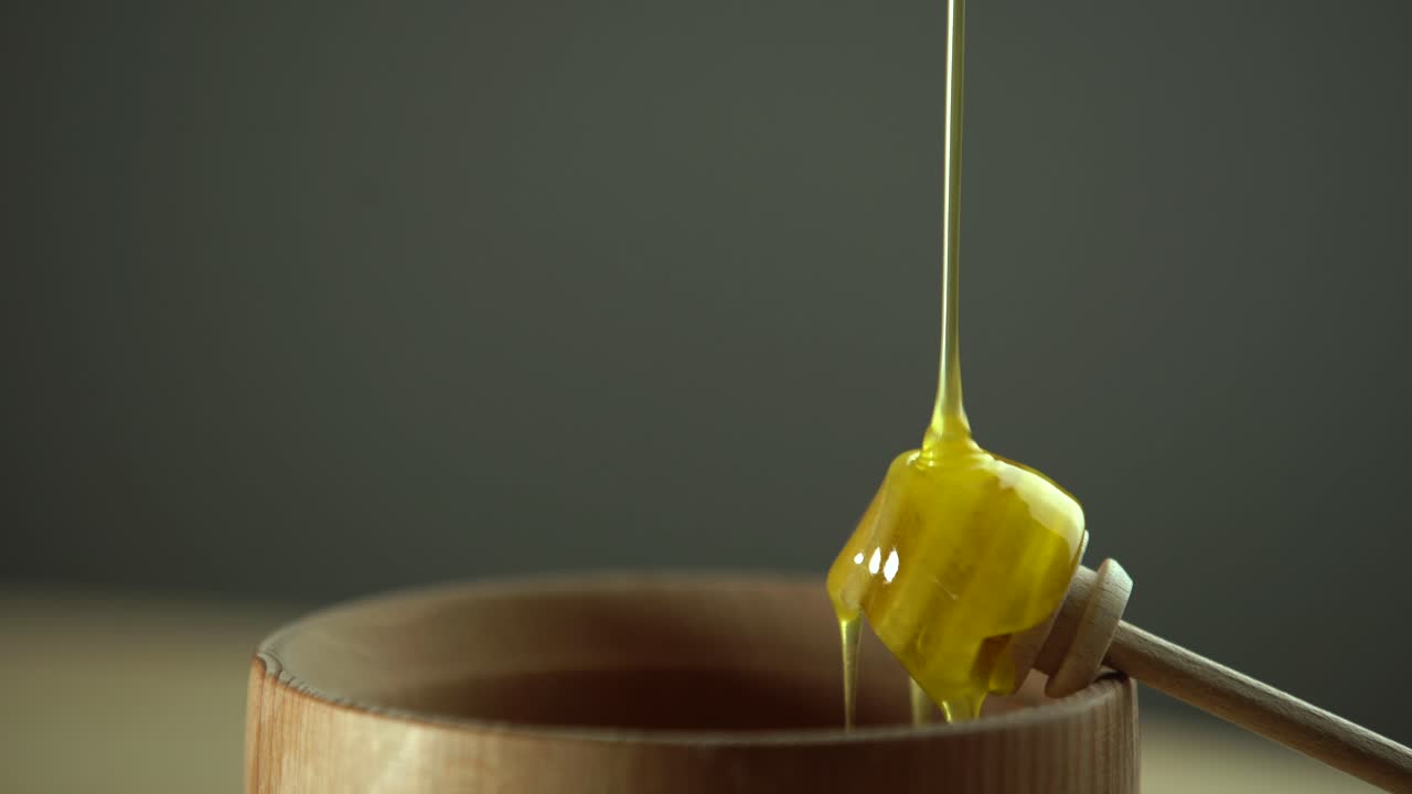 Thick honey dripping from the spoon, close up. Honey flowing honey from a spoon