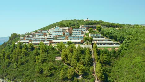 aerial dolly shot of elix mar-bella luxury hotel on forested hillside above karavostasi beach, greece