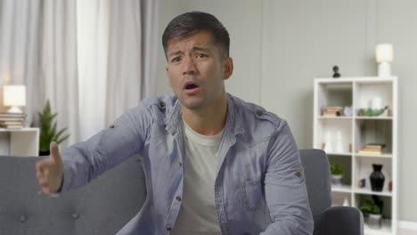 shot of disappointed young man sitting on sofa at home watching sport on tv as team loses