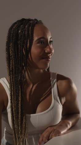 studio beauty shot of young woman with long braided hair against neutral background in profile 1