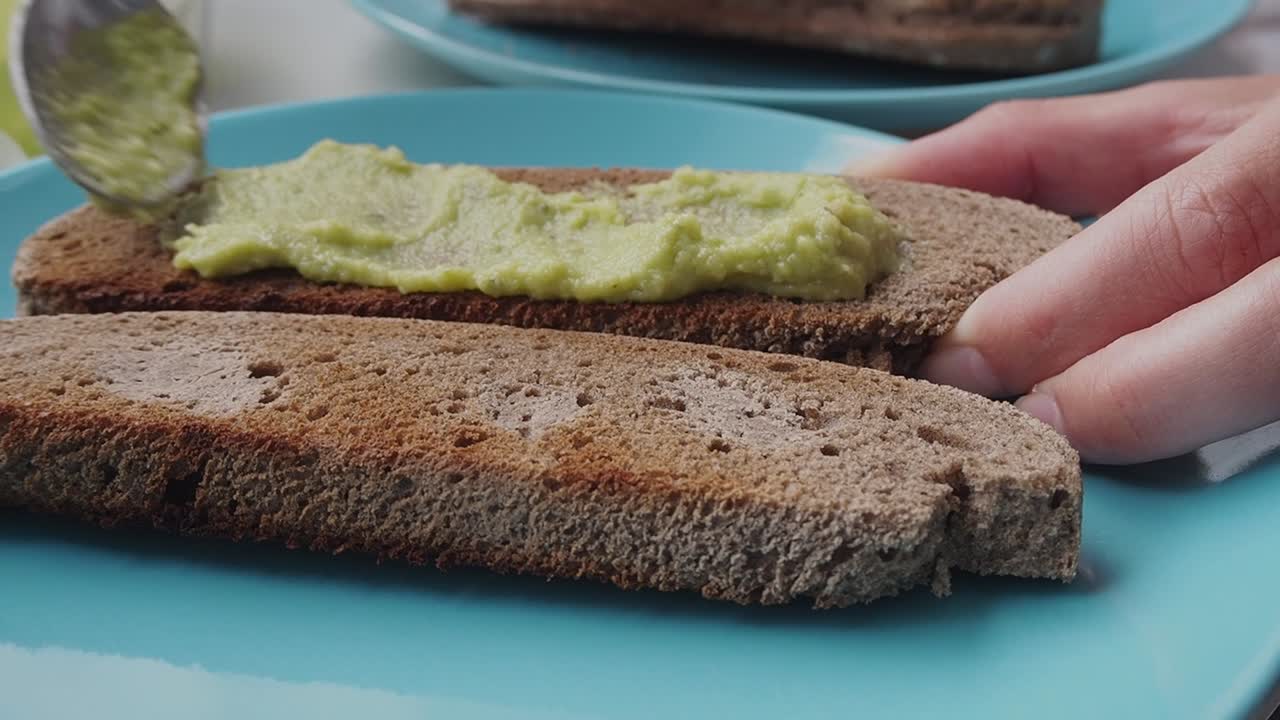 Creamy avocado spread on toasted rye bread with a spoon, close-up shot