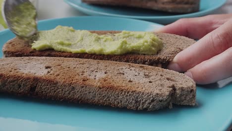creamy avocado spread on toasted rye bread with a spoon, close-up shot