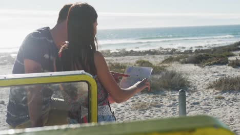 Kaukasisches-Paar-Steht-In-Der-Nähe-Eines-Strandbuggys-Am-Meer-Und-Liest-Eine-Karte