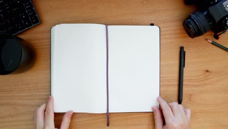 Overhead-shot-of-handwriting-in-a-black-notebook-on-a-wooden-desktop