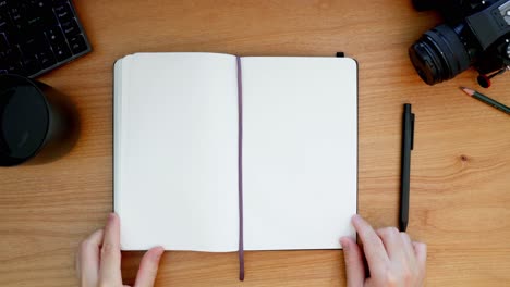 Overhead shot of handwriting in a black notebook on a wooden desktop