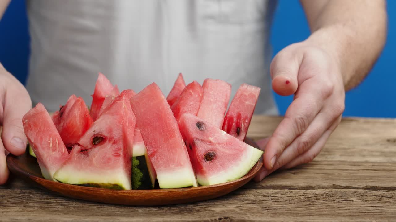 남자 손은 테이블에 개진 수박의 접시를 놓았다.