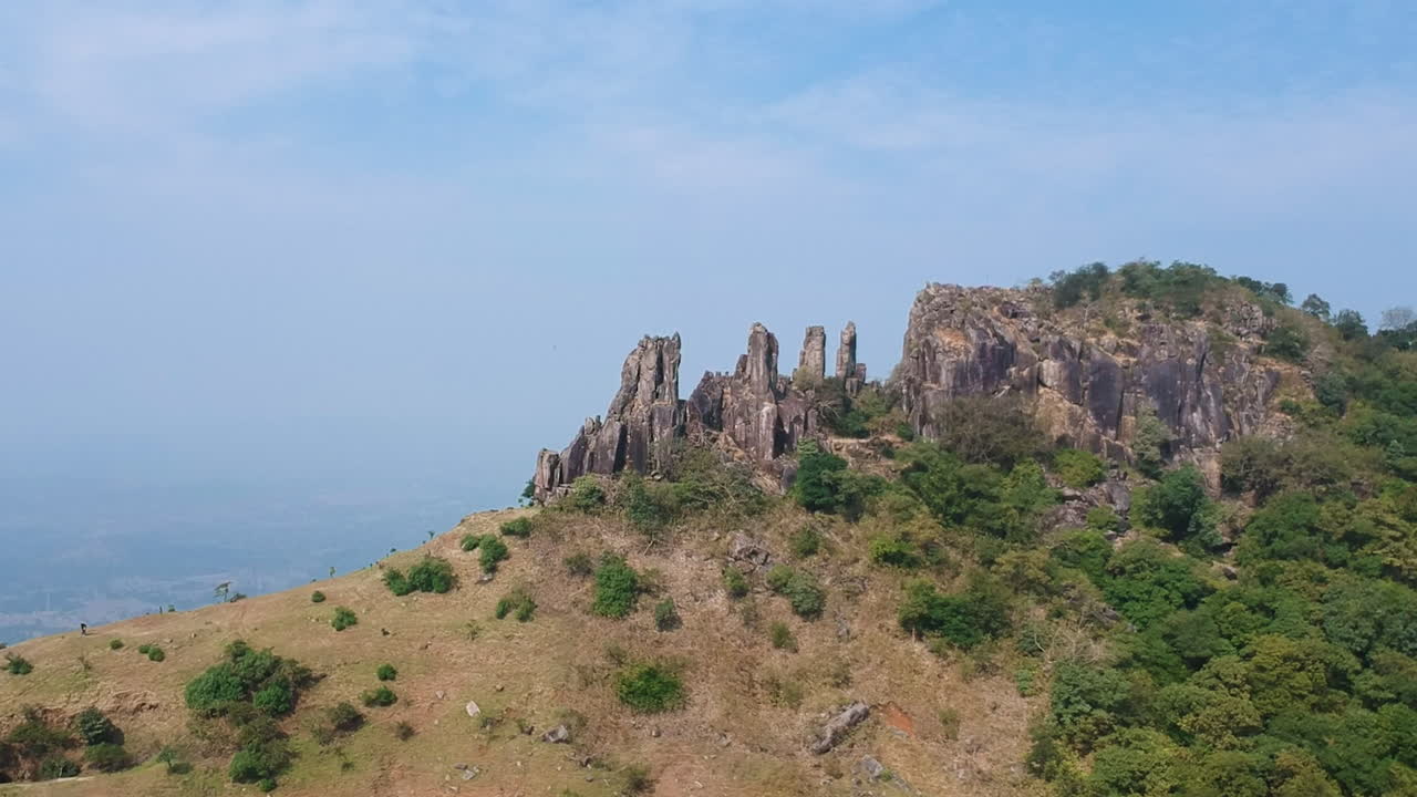 drones en círculos alrededor de la gran montaña rocosa del fuerte de ghambhirgad, maharashtra, con un cielo azul claro en el fondo