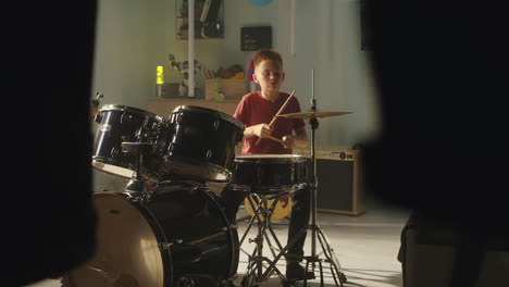 teenager learning to play drums at home teen in casual clothes playing rhythmic tune on drum kit during rehearsal in bedroom at home