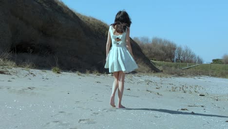 Toma-En-Cámara-Lenta-De-Una-Chica-Guapa-Con-Vestido-Blanco-Caminando-Por-La-Playa